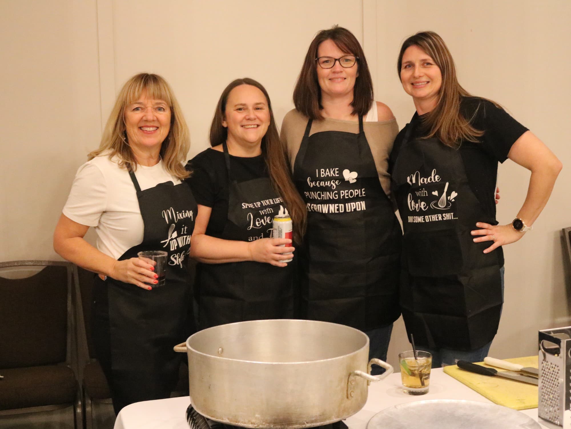 Four teammates in slogan aprons smiling behind their soup pot